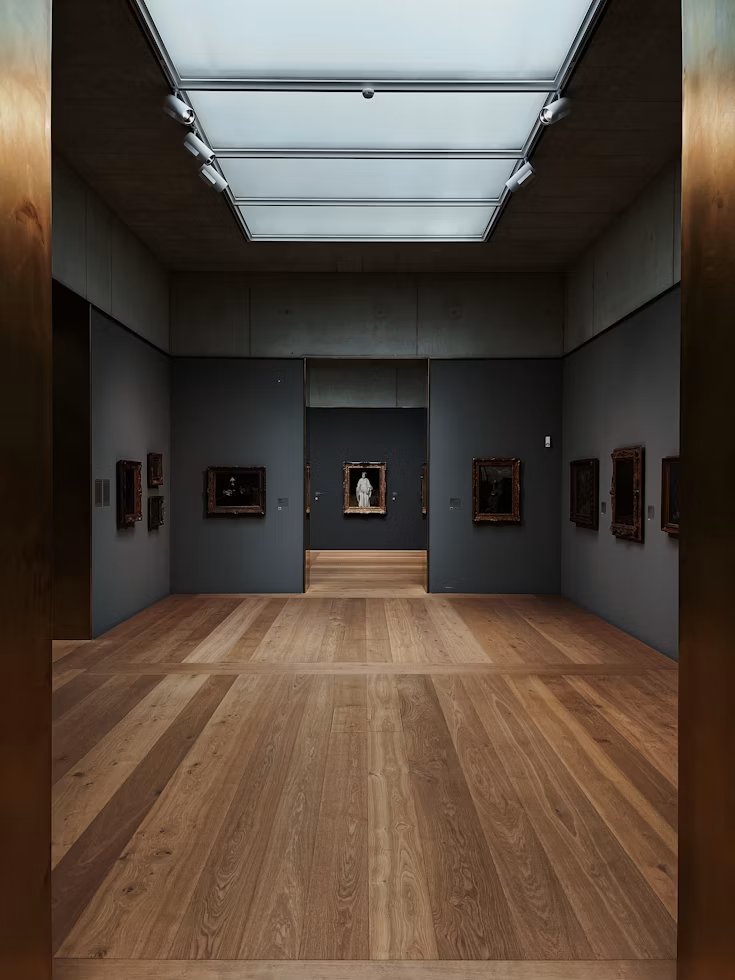 An elegant gallery room with wood flooring and framed artwork on the walls