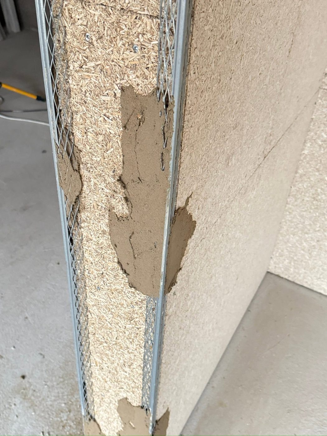 Close-up of a HEMPLITH panel edge showing the compressed hemp shiv core beneath the plaster layer
